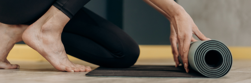 Close up of a woman's feet and hands rolling out a yoga mat